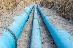 A front view of three blue water pipes in the ground.